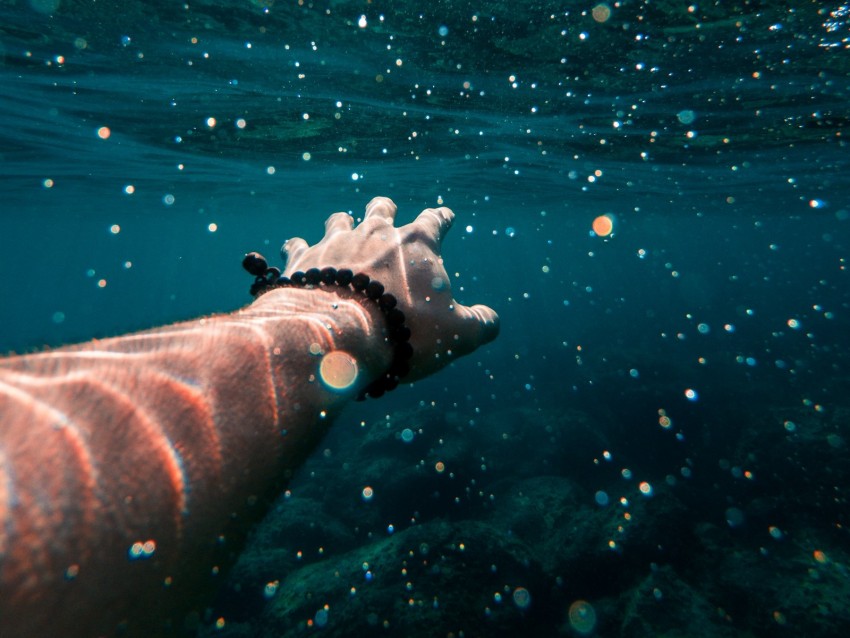 underwater photography, reaching hand, aquatic environment, sunlight reflections, mindfulness