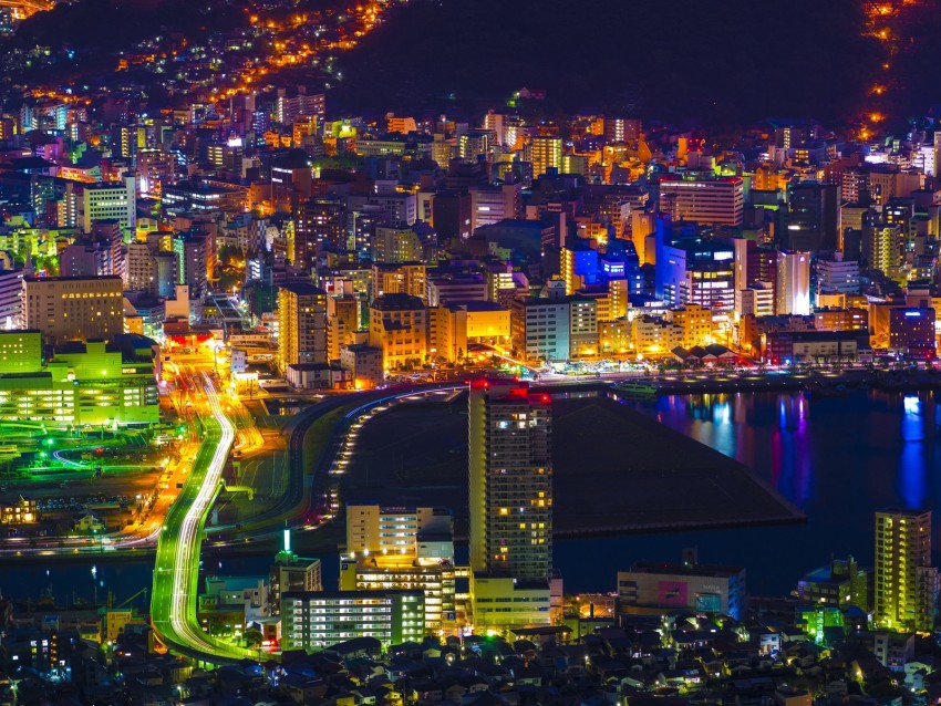 cityscape at night, urban skyline, illuminated buildings, colorful lights, waterfront view