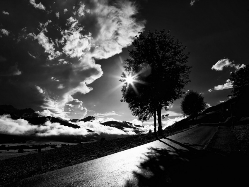 black and white landscape, dramatic clouds, silhouette tree, sunburst effect, scenic mountains